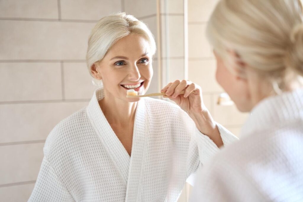 woman looks in mirror and considers how to take care of your dentures