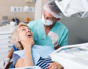 dentist talks with patient in chair about dental bridge fitting expectations