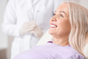 blonde woman in dentist chair gets dental implant restorations in raleigh north carolina