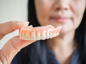 person holding retained dentures and discussing their benefits