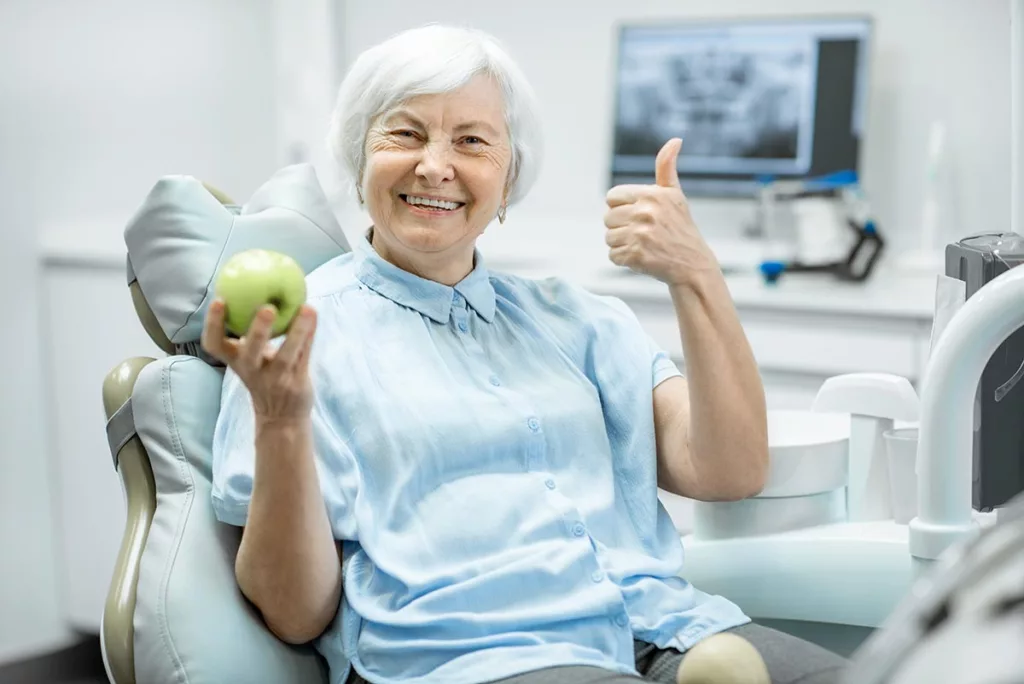 person eating apple in dental office after learning about dental implants vs mini implants