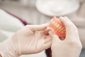 prosthodontist holding model of dentures before showing patient how should dentures fit in your mouth