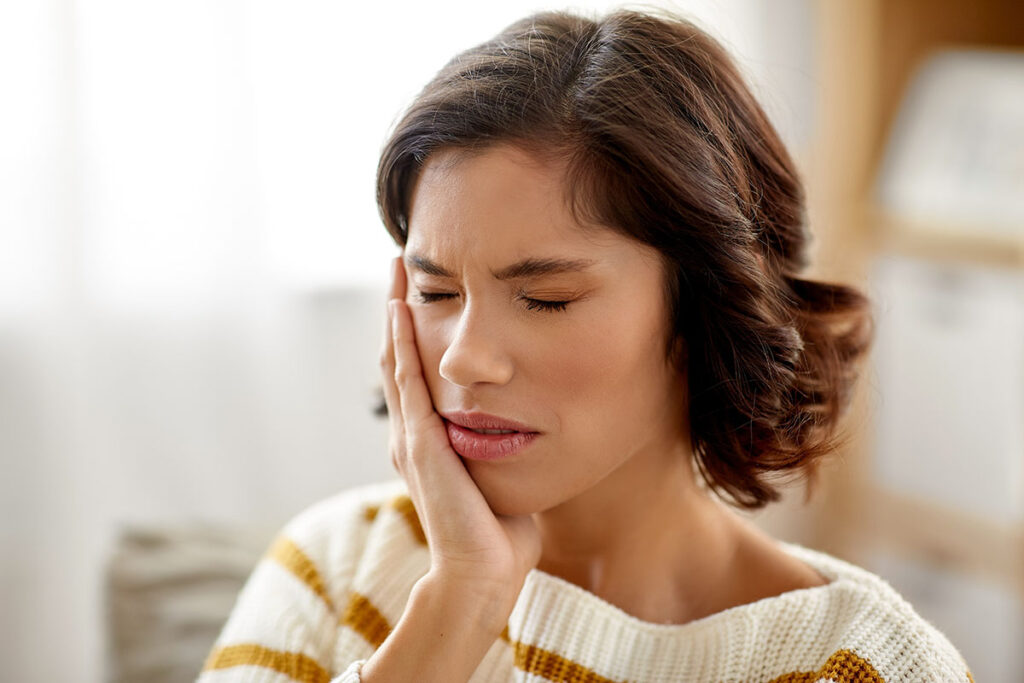 person touching face while wondering about solutions for missing teeth and oral health