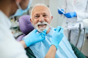 man smiles at doctor about to look at his teeth during a dental implant restoration appointment