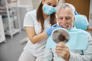 person smiling in mirror at dental office after getting dental implant options near morrisville nc