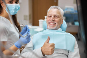 person smiling in dental chair giving thumbs up after getting dental implants in rocky mount