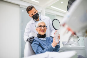 person looking in mirror after getting a smile makeover from a johnston dental provider